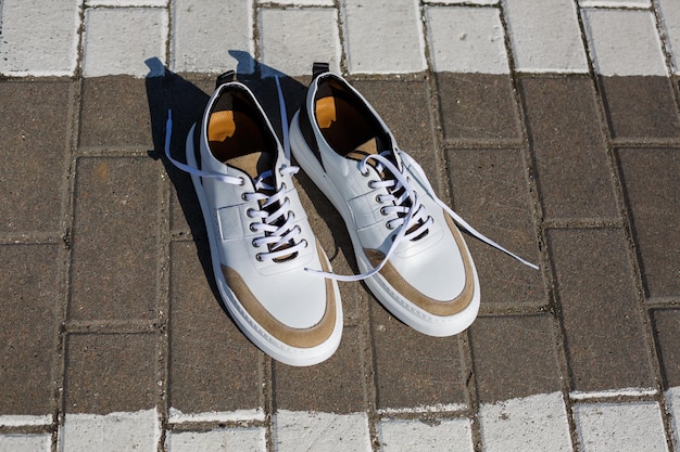 Men's feet in white everyday sneakers made of natural leather on lacing.