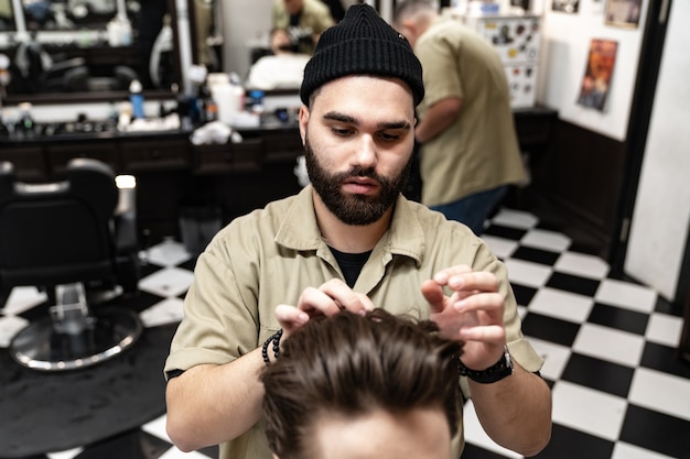 Taglio di capelli da uomo. il parrucchiere alla moda taglia un uomo. stile maschile