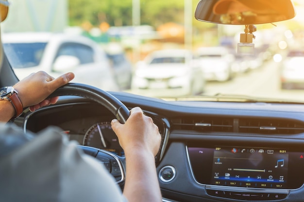 Men's hand holding steering wheel of car while driving