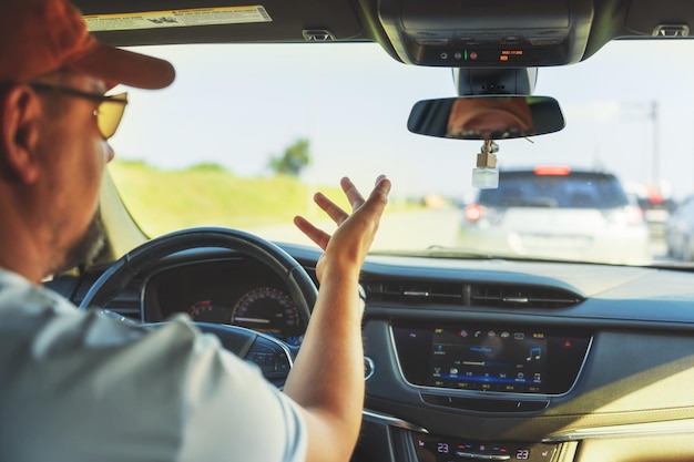 Men's hand holding steering wheel of car while driving