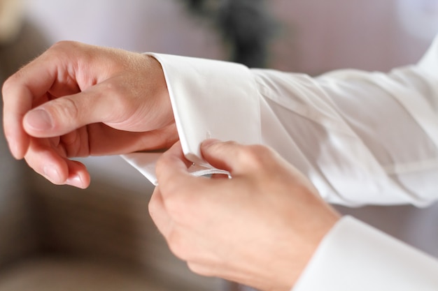 Men's hands button up the sleeves of the shirt