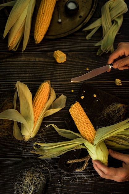 Men's hands carve corn cobs in the era of the global economic crisis and crop shortage in the dark