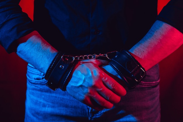 Men's hands chained in leather handcuffs for BDSM