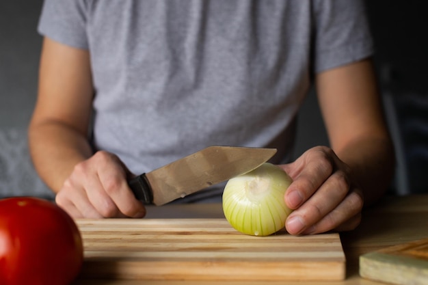 Men's hands cut onions on a wooden board
