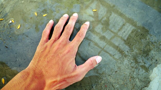 men's hands feel the water that pooled on the cement floor