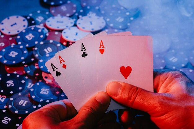 Men's hands hold aces cards against the background of playing chips. the photo shows smoke