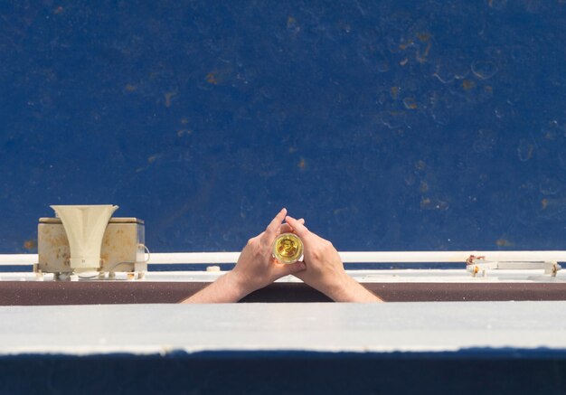 Mani di uomini che tengono bicchieri di vino su uno sfondo di ponte blu della nave