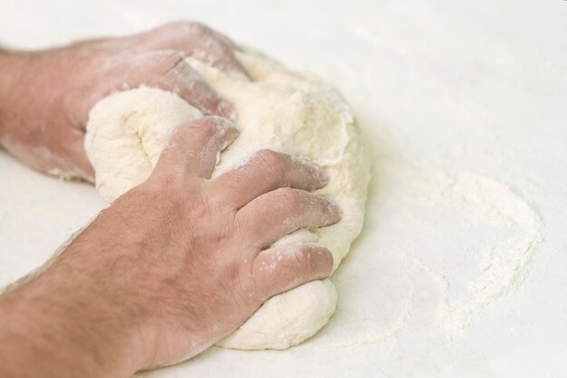 Foto le mani degli uomini impastano la pasta