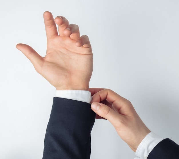 Men's hands straighten a shirt on a white