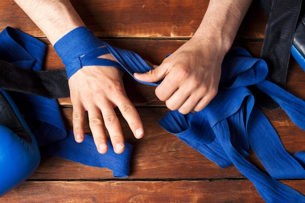 Men's hands during taping before a boxing match against a wooden surface. The concept of training for boxing training or fighting. Flat lay, top view