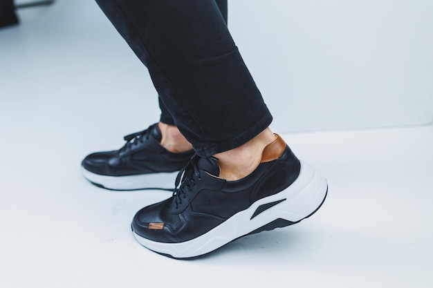 Men\'s legs in casual shoes of black color made of genuine\
leather men on shoes in black sneakers high quality photo