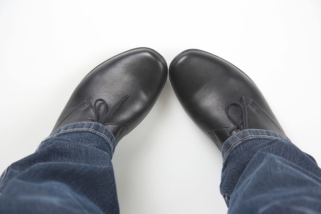 Gambe da uomo in jeans e scarpe classiche nere su sfondo bianco