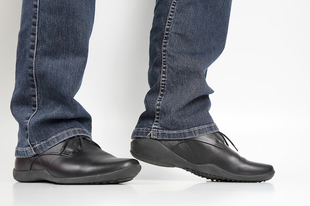 Men's legs in jeans and black classic shoes