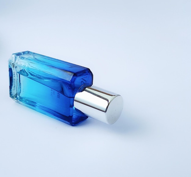 Men's perfume in a blue color glass photographed from the side isolated on white background