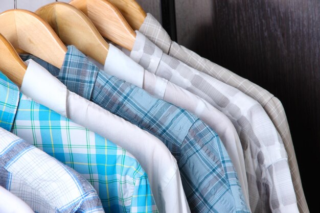 Men's shirts on hangers on wooden background