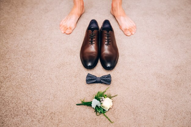 Foto scarpe da uomo in pelle marrone. concetto di matrimonio. scarpe da uomo, papillon e boutonniere, vista dall'alto.