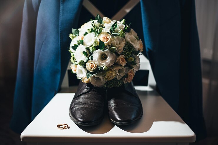 Men's shoes groom bouquet and rings on a white pedestal concept for event agency