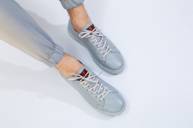 Men's sneakers on a very gray day of natural leather, men's legs shoes in gray leather shoes. High quality photo