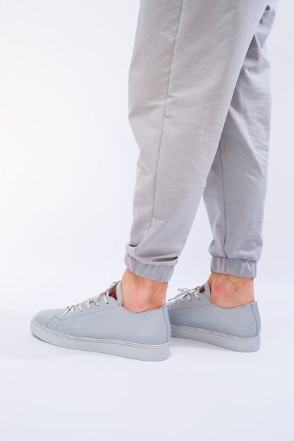 Men's sneakers on a very gray day of natural leather, men's legs shoes in gray leather shoes. High quality photo