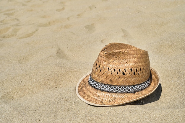 Cappello da spiaggia di paglia da uomo sulla sabbia in spiaggia closeup copia spazio per il testo una bella giornata di sole concetto di vacanza estiva