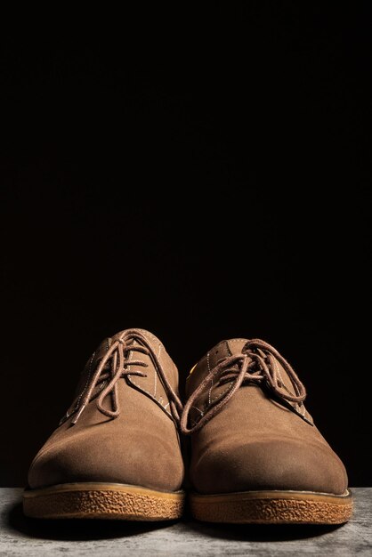 Men's suede brown low shoes with laces on a black background Vertical copy space