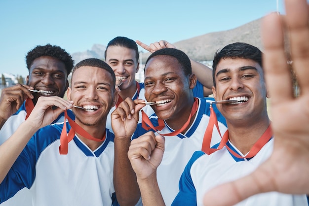 Selfie メダルと勝者のサッカー競技会とフィールドの多様性と成功のスポーツ選手グループの男性の肖像画の若い男性サッカー選手とチームの笑顔で写真の勝利と賞品