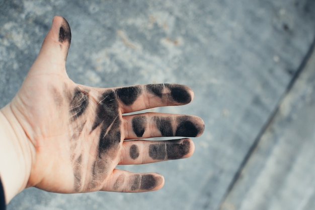 Men show their dirty hands with palms up, in a black oil