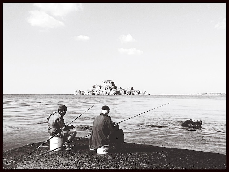 Photo 空の向こうの湖で釣り竿を持って座っている男性