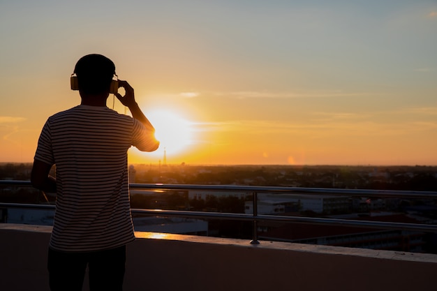 Men standing on headphones at sunset