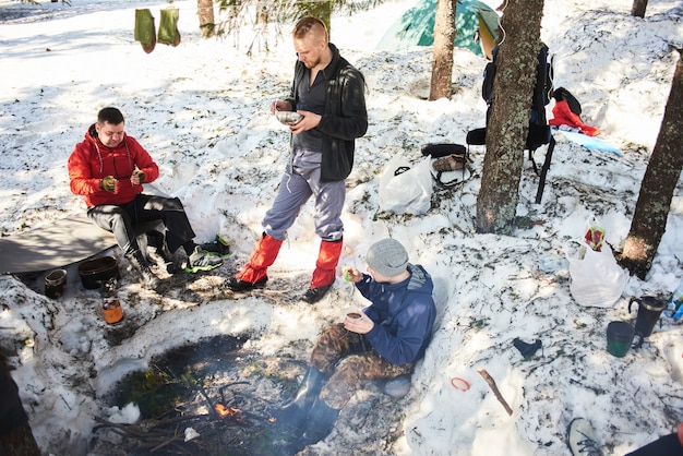 Men, tourists eat in the forest near a fire