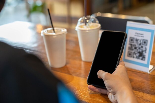 Men use phones to scan a qr code to select a menu or scan to\
receive a discount or pay for food and drink inside a cafe using\
the phone to transfer money or pay online without cash concept