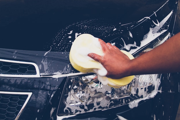 Мужчины используют желтую губку для мытья автомобиля