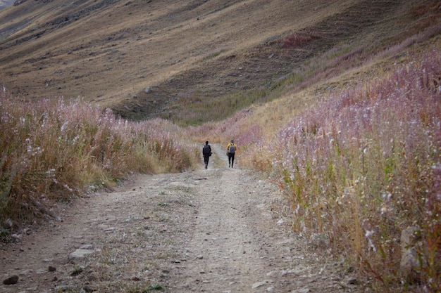 Gli uomini camminano in montagna lungo una strada sterrata