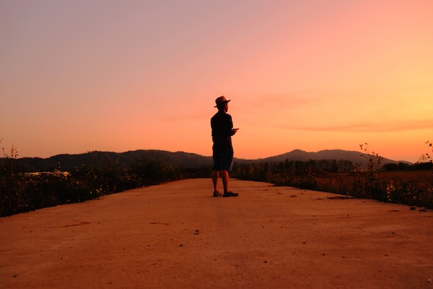 Men wearing striped shirts and straw hats stand at sunset.