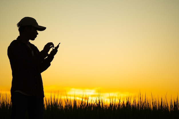 Gli uomini che indossano camicie a righe con un berretto stanno per usare il telefono al tramonto con copia spazio.silhouette di un uomo con un cappello che usa un telefono.