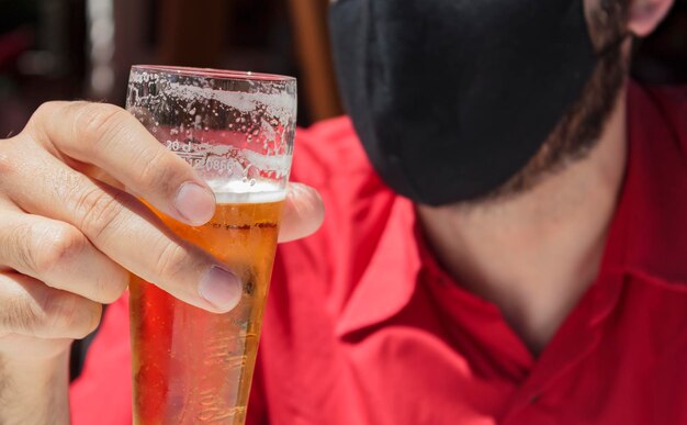 Foto uomini con maschera protettiva che tengono un bicchiere di birra