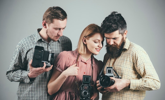 Men woman on concentrated faces looks at camera grey background Men in checkered clothes retro style Vintage photography concept Company of busy photographers with old cameras filming working