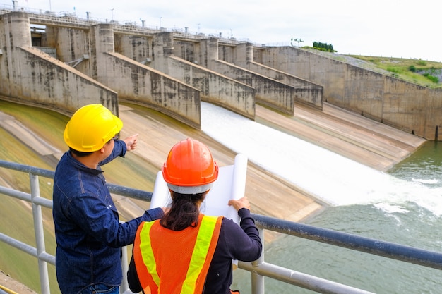 Men and woman meeting with Engineers and supervisors are standing reading the blueprints 