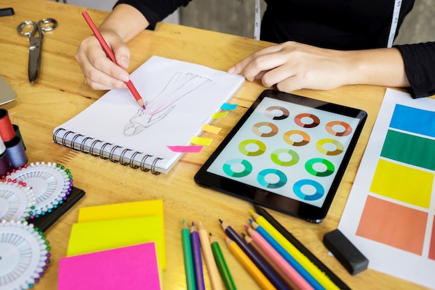 Uomini che lavorano come stilista scegliendo sulla tabella di colore per i vestiti in tavoletta digitale sul posto di lavoro dello studio.