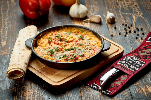 Menemen with eggs tomato green peppers and spices served with bread in pan Turkish breakfast