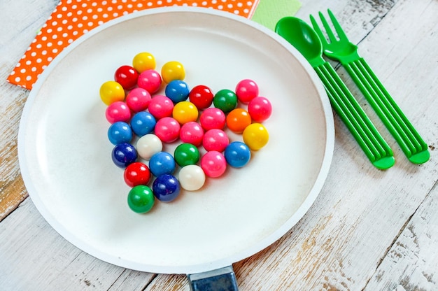 meng kleurrijke chocoladesnoepjes in hartvorm op een witte pan