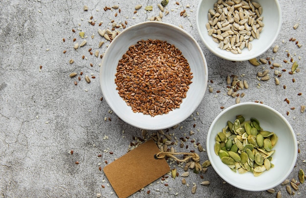 Meng verschillende zaden voor een gezonde salade, kommen op een grijze betonnen ondergrond