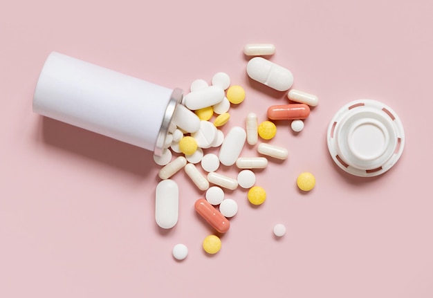 Foto mengsel van medische capsules en pillen met een fles op lichtroze bovenkant behandeling met geneesmiddelen inname van voedingssupplementen en vitaminen verschillende farmaceutische producten