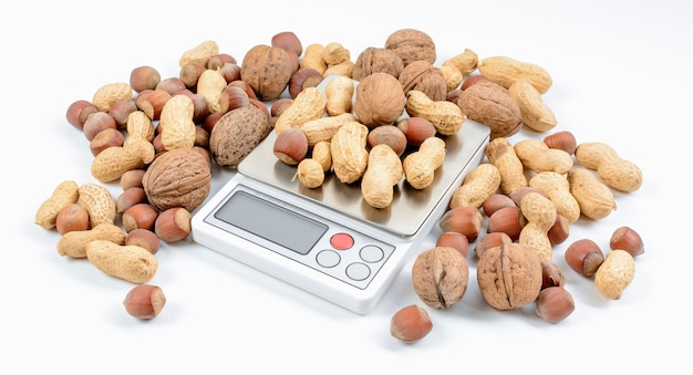 Foto mengsel van noten op elektronische weegschaal met witte achtergrond. dieet en gewichtsverlies concept.