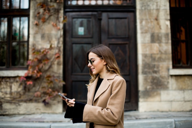 Mening bij moderne vrouw die mobiele telefoon met behulp van bij de herfst openlucht