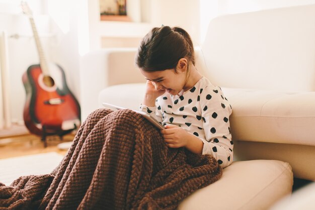 Mening bij mooie kleine meisjeszitting op de vloer die de tablet houdt