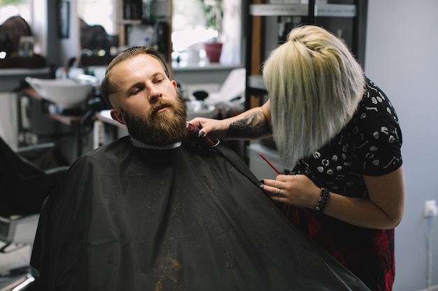 Mening van de jonge gebaarde mens die baardkapsel krijgen door kapper bij herenkapper.
