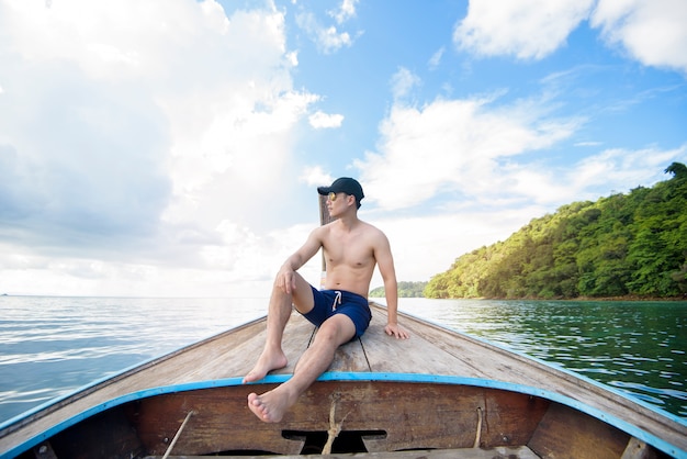 Mening van de mens in zwempak die op Thaise traditionele longtailboot over mooie berg en oceaan genieten