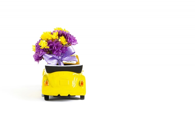 Mening van een kleurrijk boeket van purpere bloemen dat in een kleine gele auto is. Selectieve aandacht. Het concept van een vakantie, bruiloft, bloemen bezorgen, cadeau