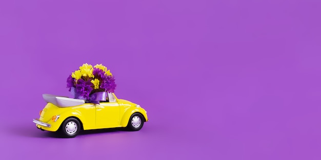 Mening van een kleurrijke gele converteerbare auto met een boeket bloemen op een roze dat de blauwe wolk in de vorm van een hart verlaat. Concept vakantie, levering, kunst, transport